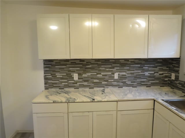 kitchen featuring decorative backsplash, white cabinets, and sink