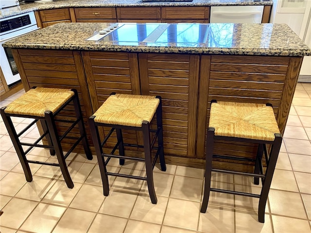 exterior space featuring black electric stovetop, light stone counters, and light tile patterned flooring