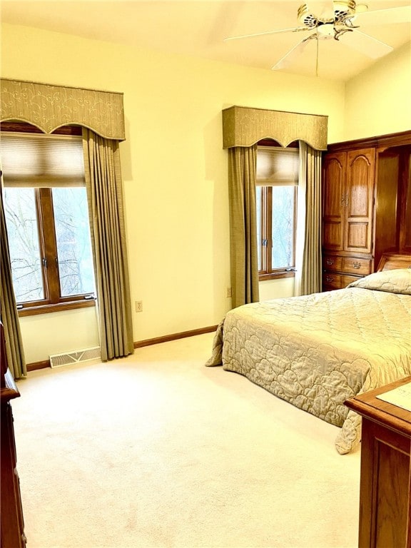 bedroom featuring multiple windows, ceiling fan, and light colored carpet