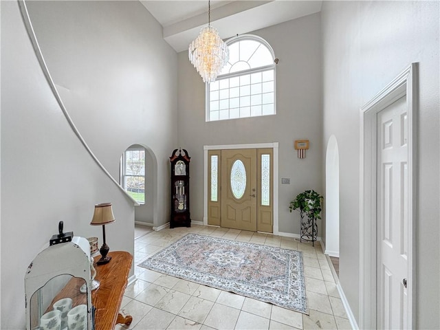 tiled foyer entrance with a high ceiling and an inviting chandelier