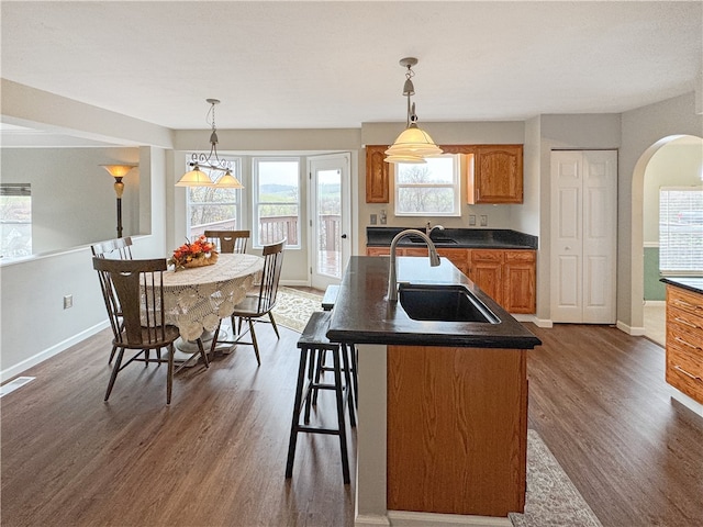 kitchen with dark hardwood / wood-style flooring, a center island with sink, and hanging light fixtures