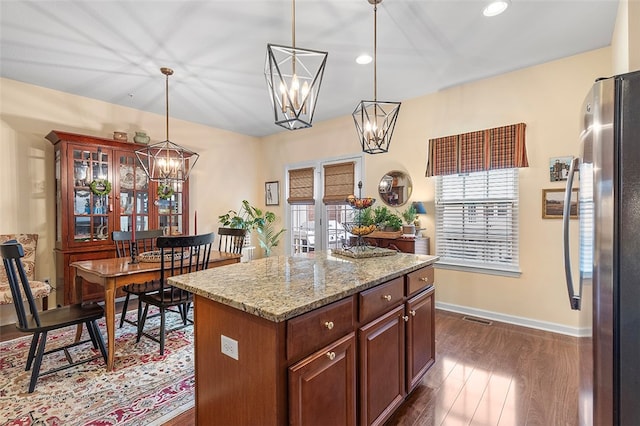 kitchen featuring a wealth of natural light, a center island, dark wood-type flooring, stainless steel fridge, and pendant lighting