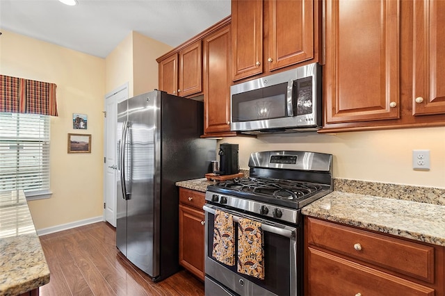 kitchen with light stone countertops, dark wood-type flooring, and stainless steel appliances