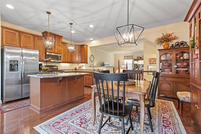 kitchen featuring light stone counters, pendant lighting, dark wood-type flooring, and appliances with stainless steel finishes