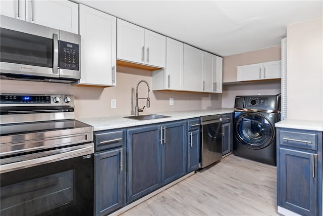 kitchen with sink, blue cabinetry, white cabinetry, stainless steel appliances, and washer / clothes dryer