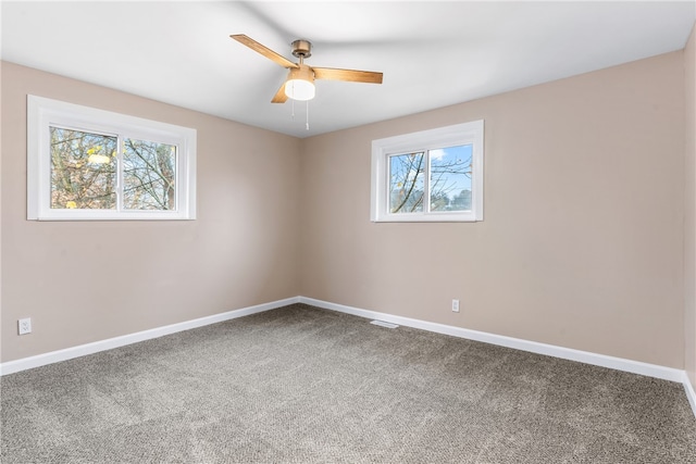 spare room with carpet flooring, a wealth of natural light, and ceiling fan