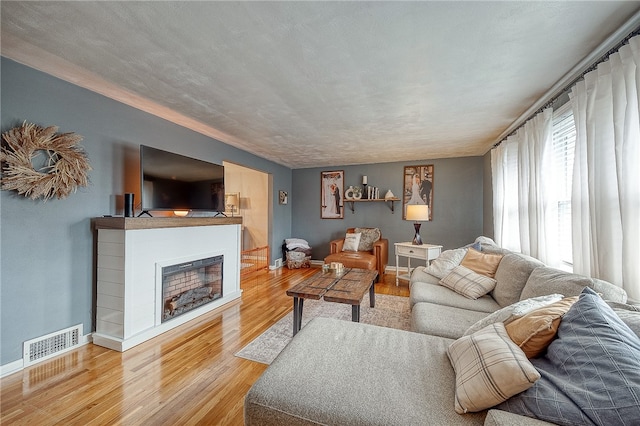 living room featuring light wood-type flooring and a textured ceiling