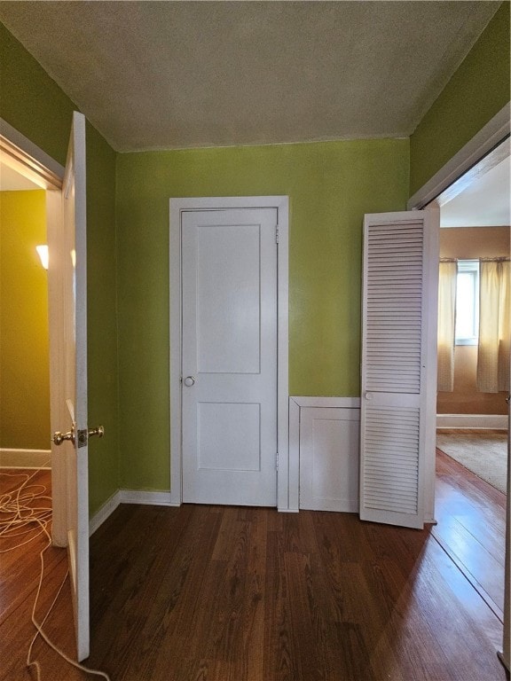 unfurnished bedroom with a textured ceiling, dark hardwood / wood-style floors, and a closet