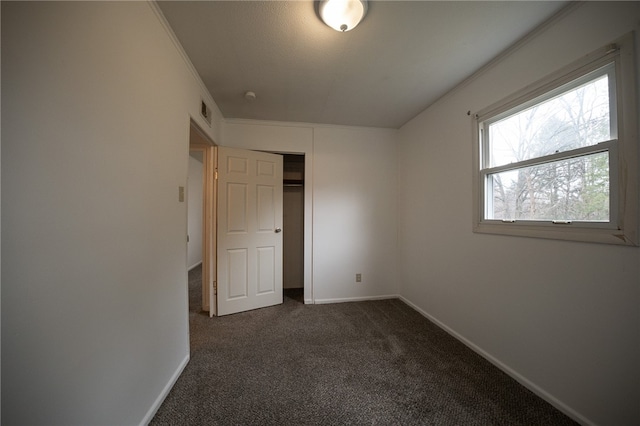 unfurnished bedroom featuring dark colored carpet and crown molding