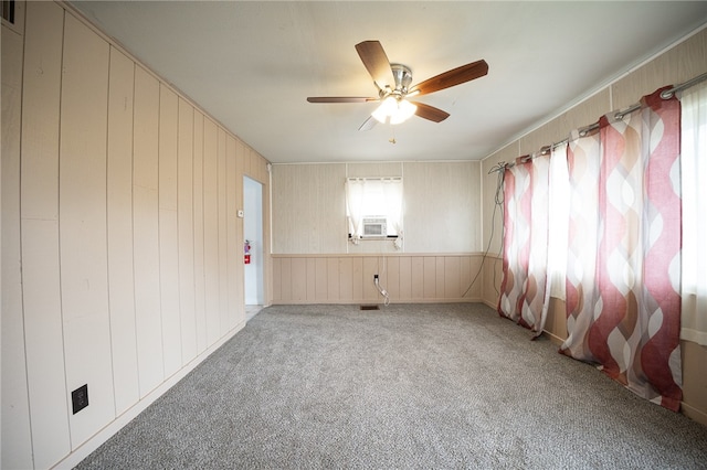 empty room with carpet, ceiling fan, and wooden walls