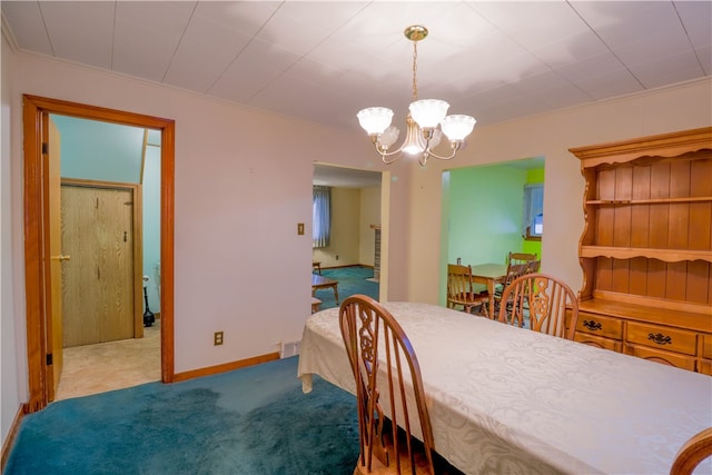 carpeted dining space with a chandelier and ornamental molding