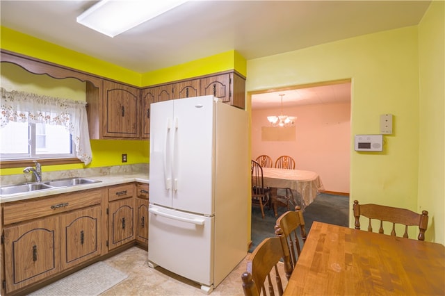 kitchen featuring white fridge, an inviting chandelier, hanging light fixtures, and sink