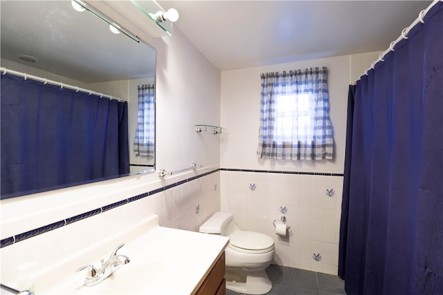 bathroom featuring tile patterned floors, vanity, toilet, and tile walls