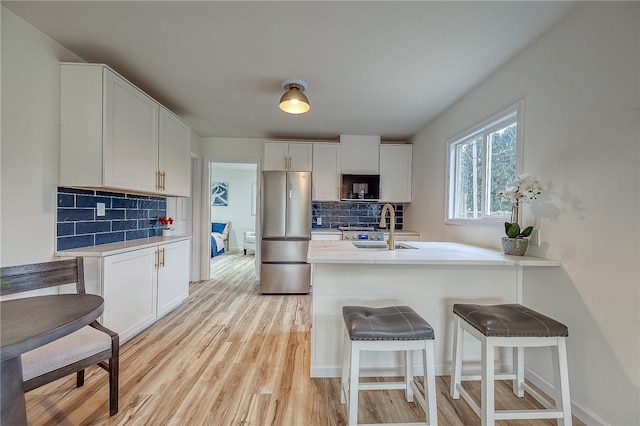 kitchen featuring white cabinets, backsplash, and stainless steel fridge