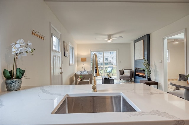 kitchen featuring ceiling fan, a fireplace, and sink