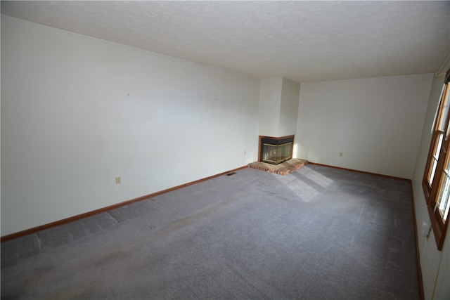 empty room featuring a fireplace, a textured ceiling, and carpet floors