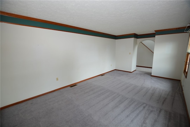 carpeted empty room with ornamental molding and a textured ceiling