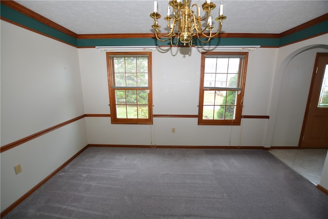 carpeted spare room with a chandelier, a healthy amount of sunlight, and a textured ceiling