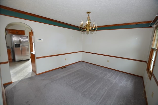 unfurnished room with a textured ceiling, ornamental molding, light carpet, and an inviting chandelier