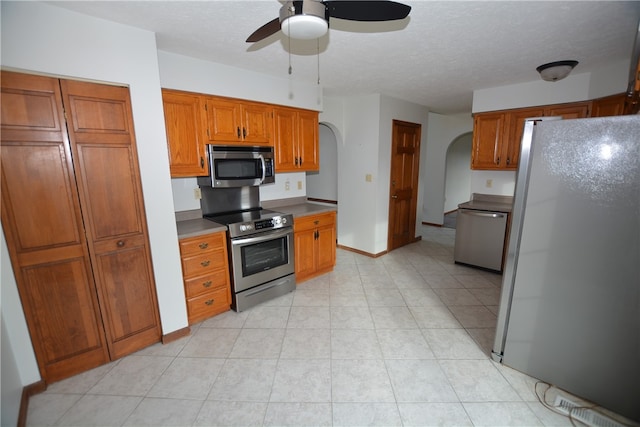 kitchen featuring appliances with stainless steel finishes, a textured ceiling, light tile patterned floors, and ceiling fan