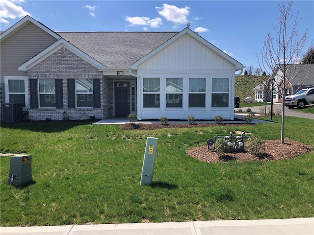 view of front of home with central air condition unit and a front yard