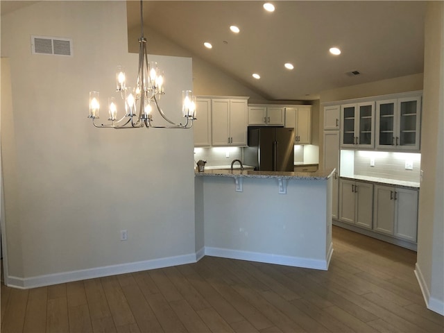 kitchen featuring white cabinets, decorative light fixtures, hardwood / wood-style floors, and stainless steel refrigerator