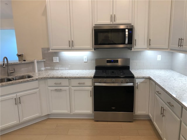 kitchen featuring white cabinetry, light stone countertops, sink, and appliances with stainless steel finishes