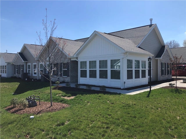 back of house featuring a sunroom, a yard, and central air condition unit