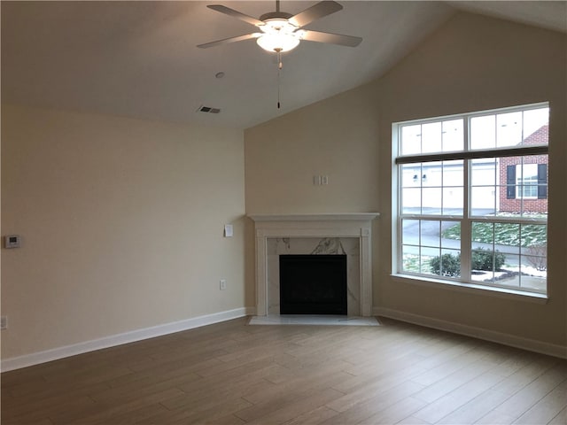 unfurnished living room featuring ceiling fan, wood-type flooring, a high end fireplace, and vaulted ceiling