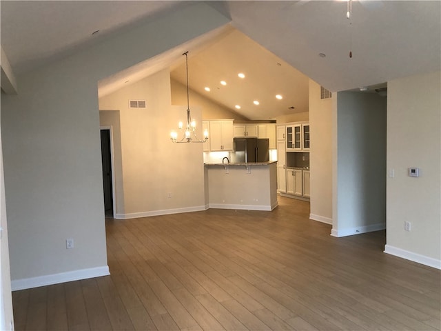 unfurnished living room featuring dark hardwood / wood-style flooring, lofted ceiling, sink, and a chandelier