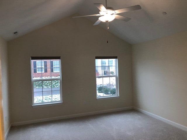 carpeted spare room featuring vaulted ceiling and ceiling fan