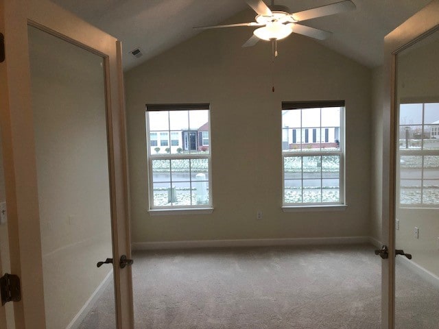 unfurnished room featuring light carpet, vaulted ceiling, and ceiling fan