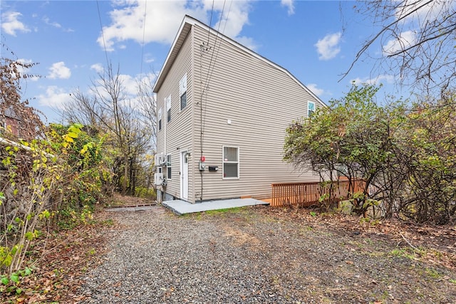 view of property exterior featuring a wooden deck and a patio