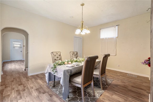 dining room with wood-type flooring and a notable chandelier