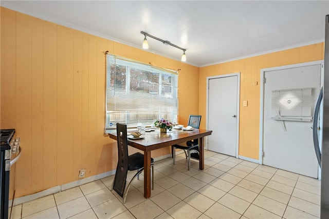 dining area with wood walls, ornamental molding, rail lighting, and light tile patterned floors