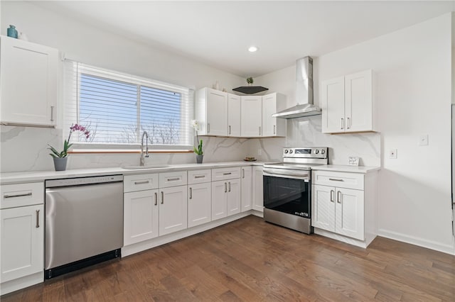 kitchen with wall chimney exhaust hood, stainless steel appliances, sink, white cabinets, and dark hardwood / wood-style floors