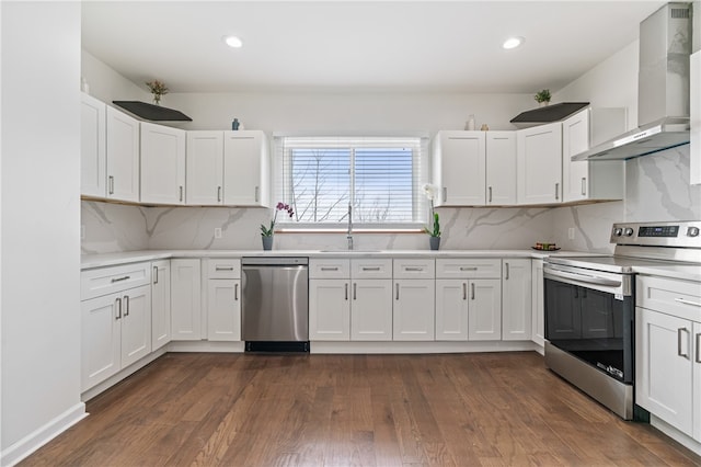 kitchen with white cabinetry, dark hardwood / wood-style flooring, wall chimney exhaust hood, and appliances with stainless steel finishes