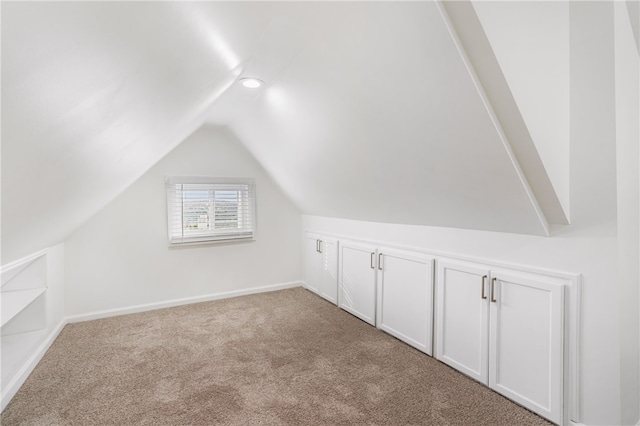 additional living space featuring light colored carpet and lofted ceiling