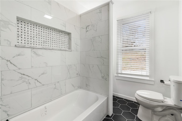 bathroom featuring tile patterned floors, tiled shower / bath, and toilet