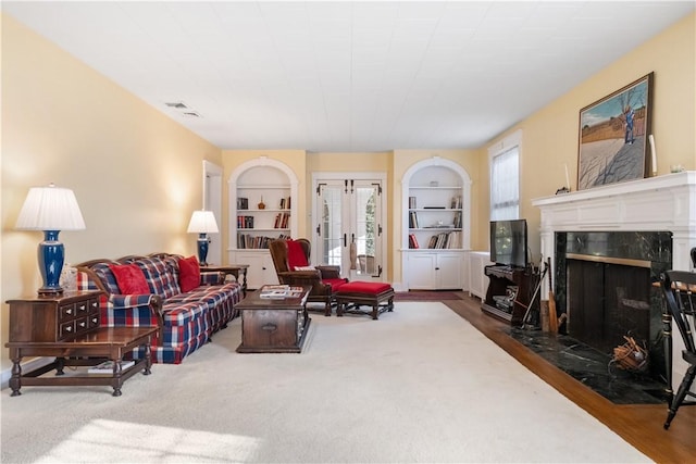 living room featuring built in shelves, french doors, and a fireplace