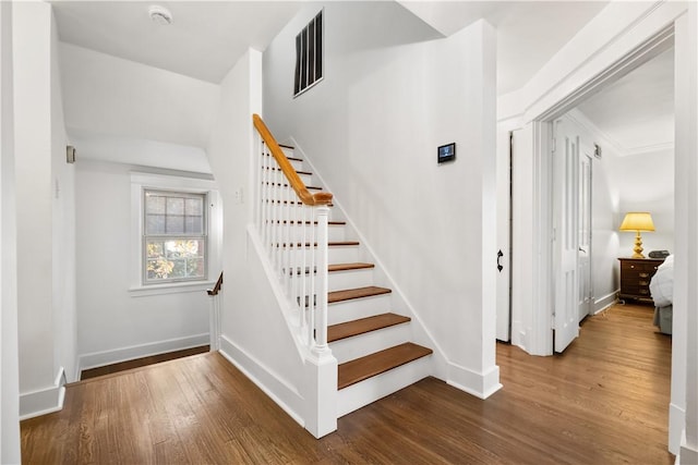 stairway with visible vents, baseboards, and wood finished floors