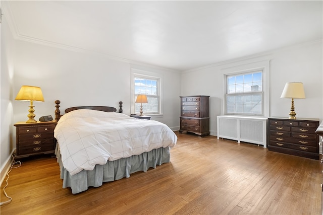 bedroom with radiator heating unit, wood-type flooring, and ornamental molding