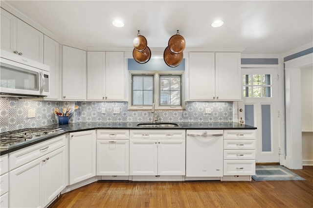 kitchen with tasteful backsplash, sink, light hardwood / wood-style floors, and white appliances