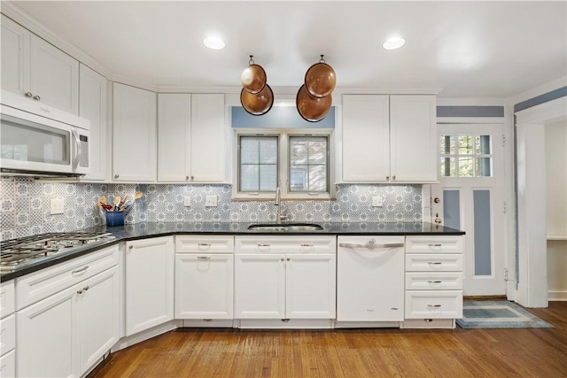 kitchen featuring white appliances, light wood-type flooring, a sink, and white cabinets