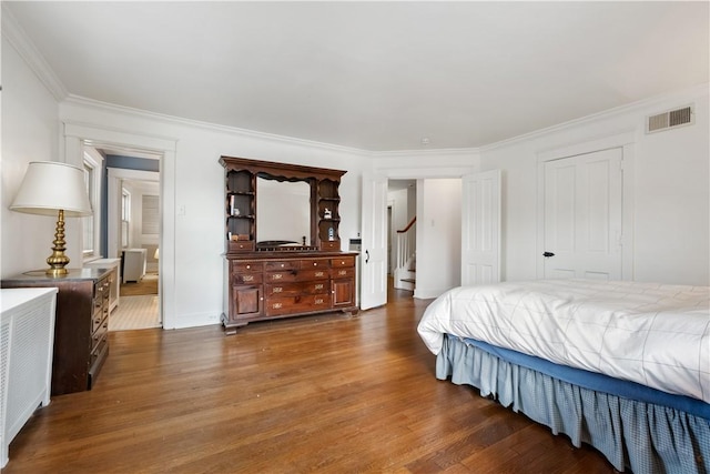 bedroom featuring visible vents, dark wood finished floors, and ornamental molding