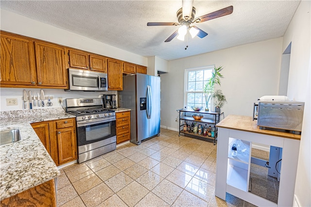 kitchen with a textured ceiling, stainless steel appliances, and ceiling fan