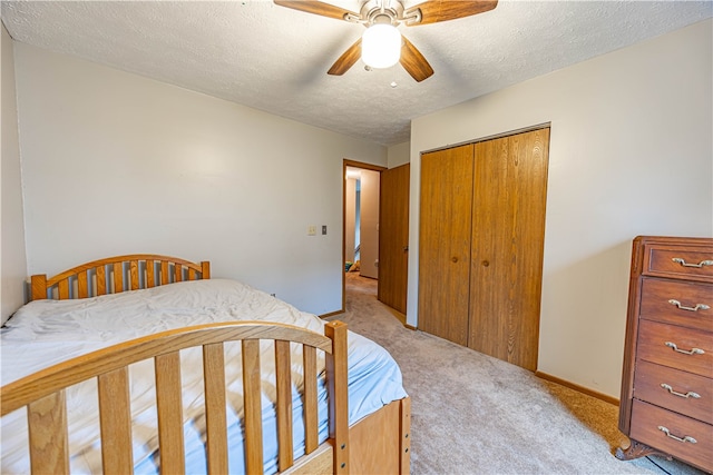 bedroom featuring light carpet, a textured ceiling, a closet, and ceiling fan