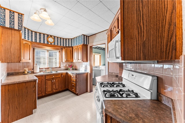 kitchen featuring washing machine and clothes dryer, decorative backsplash, sink, and white appliances