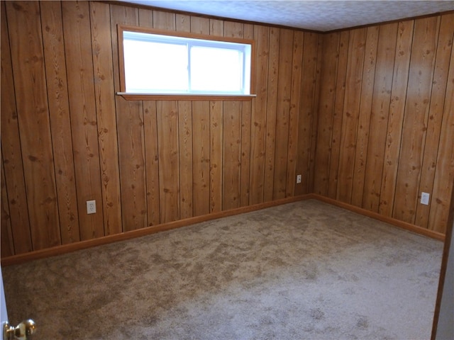 carpeted empty room featuring a textured ceiling and wooden walls