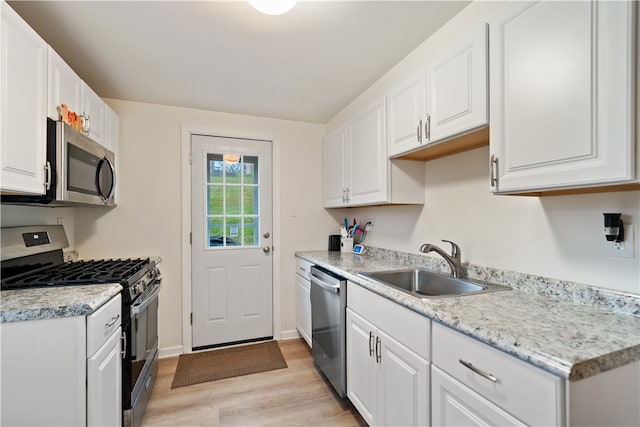 kitchen featuring white cabinets, sink, light hardwood / wood-style flooring, light stone countertops, and stainless steel appliances